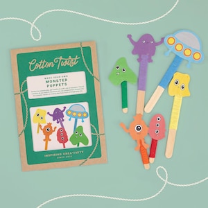 May include: A craft kit with the text "Cotton Twist" and "Make Your Own Monster Puppets." The kit includes a set of colorful monster puppets made of wood and yarn. The puppets are in various shapes and colors, including purple, orange, and green.