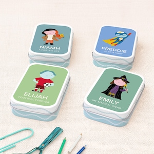 May include: Four rectangular metal tins with rounded corners, each featuring a unique cartoon character and name. The tins display Niamh with a pirate theme, Freddie as a superhero, Elijah with a soccer ball, and Emily as a witch with a wand.