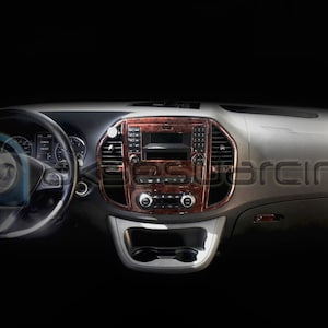 Puede incluir: Un interior de coche negro con un salpicadero de madera marrón y un volante. El salpicadero tiene una radio y botones de control del clima.