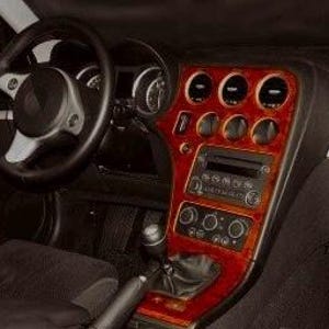 Pode incluir: Vista interior do painel de instrumentos de um carro. O painel apresenta um acabamento em grão de madeira vermelha com detalhes em preto. O volante é preto com detalhes prateados. Medidores e controles são visíveis.