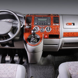 May include: The interior of a van with a wood-grain dashboard, a steering wheel, and two seats. The seats are covered in a patterned fabric.