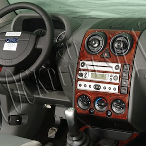 Puede incluir: Primer plano del interior de un coche con un kit de moldura de salpicadero de imitación de madera. El kit incluye un marco para la radio, marcos para las salidas de aire y una moldura para la consola central. El kit está diseñado para dar al interior del coche un aspecto más lujoso.