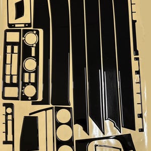 Puede incluir: Un conjunto de pegatinas decorativas de interior en negro brillante para habitáculo de vehículo, dispuestas sobre una hoja de soporte beige. La colección incluye varias formas geométricas, tiras rectangulares y recortes circulares, con el texto MARS cockpit design.