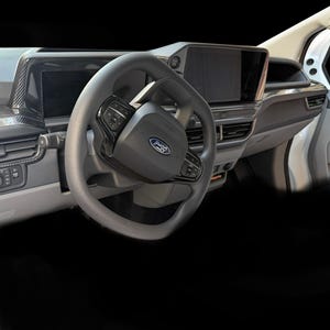 Peut inclure: Vue intérieure d'un véhicule Ford, mettant en évidence le tableau de bord et le volant. Le volant noir est équipé de commandes intégrées et du logo Ford. Le tableau de bord comprend un grand écran d'infodivertissement et des garnitures en fibre de carbone. L'intérieur est principalement gris et noir.