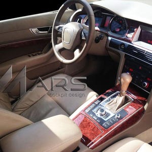 May include: The interior of a vehicle featuring beige leather seats, a steering wheel, and a centre console with a gear shifter. The dashboard and console are accented with polished wood trim. The text MARS cockpit design is visible on the image.