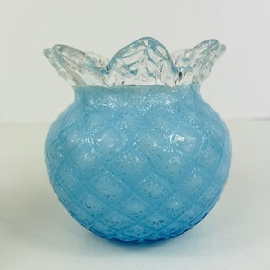 May include: A light blue glass vase with a textured, diamond-shaped pattern and a clear, ruffled top.