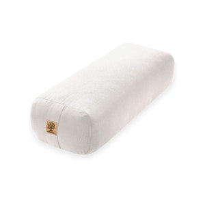 May include: A white rectangular yoga bolster with a brown label that says "Manduka".
