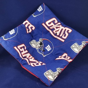 May include: Blue and red quilted hot pad with a repeated pattern of the New York Giants logo and the word "Giants".