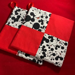 May include: Two red and white Christmas stockings with a Mickey Mouse pattern. The stockings are made of fabric and have a loop at the top for hanging.