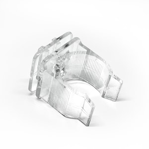 May include: A clear plastic clip for hanging items. The clip has a U-shaped design with a locking mechanism.