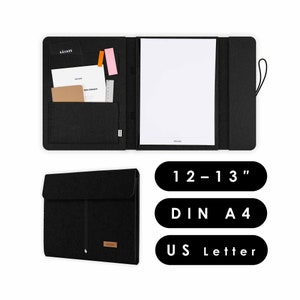 May include: Black felt folder with a zipper closure and a small pocket on the front. The folder is open to reveal a white sheet of paper and a smaller pocket with a ruler and a notepad. The folder is labelled "12-13", "DIN A4", and "US Letter".