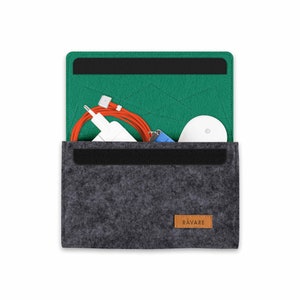 Könnte beinhalten: Eine graue Filztasche mit grünem Filz-Innenfutter. Die Tasche hat einen schwarzen Reißverschluss und ein braunes Leder-Etikett mit dem aufgedruckten Wort "RAVARE". Die Tasche ist offen und enthält ein weißes Ladegerät, ein orangefarbenes Kabel und einen weißen kabellosen Ohrhörer.