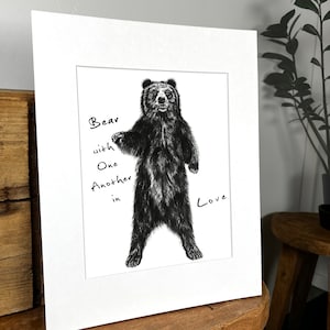 May include: Black and white illustration of a bear standing on its hind legs with the text "Bear with one another in love" written on the image.
