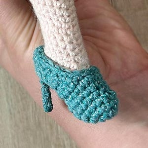 May include: A teal blue crocheted shoe with a pointed toe and a small heel.