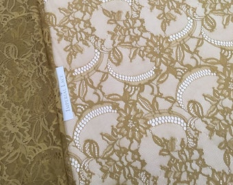 May include: A close-up of a gold lace fabric with a floral pattern. The fabric has a delicate, intricate design and is perfect for crafting or sewing projects.