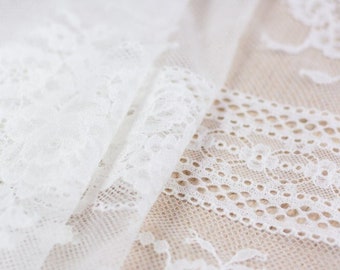 May include: White lace fabric with a delicate floral pattern. The fabric is soft and sheer, and it has a subtle sheen.