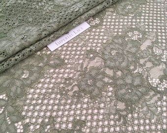 May include: Sage green floral lace fabric with a delicate pattern. The fabric has a soft, flowing texture and is perfect for creating garments, accessories, or home decor.