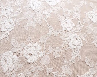 Puede incluir: Tela de encaje blanca con un delicado patrón floral. El encaje es transparente y tiene una sensación suave y femenina.