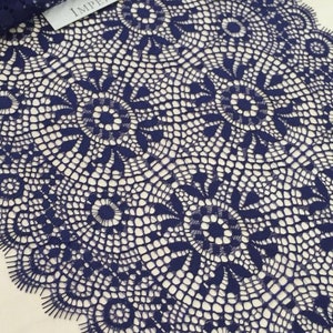 May include: Navy blue lace trim with a delicate floral pattern. The lace has a scalloped edge and is perfect for adding a touch of elegance to any project.