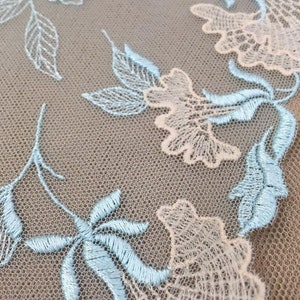 K&ouml;nnte beinhalten: Hellblauer und wei&szlig;er Blumenspitzenstoff mit einem zarten Muster. Die Spitze ist mit einem Blumenmuster bestickt und hat ein weiches, luftiges Gef&uuml;hl.