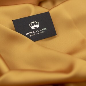 May include: A black business card with a white crown and the text "IMPERIAL LACE french lace dealer" on a gold fabric background.
