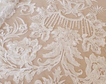May include: White beaded lace fabric with a floral pattern. The fabric has a delicate, intricate design with small beads and sequins. The label "Imperial Lace" is visible in the top left corner of the image.