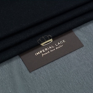 Könnte beinhalten: Schwarzer, durchsichtiger Stoff mit einem dezenten Glitzereffekt. Auf dem Stoff liegt eine braune Karte mit dem Text "IMPERIAL LACE french lace dealer".