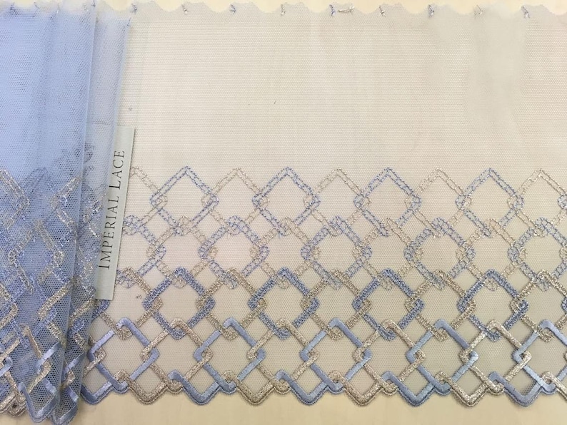 May include: Blue and gold geometric lace trim with a scalloped edge. The trim features a repeating pattern of squares and diamonds. The label reads "Imperial Lace".