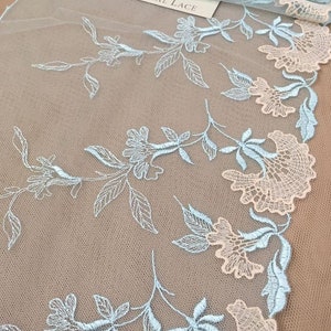 K&ouml;nnte beinhalten: Hellblaue und pfirsichfarbene florale Spitzenstoff mit dem Text "Imperial Lace" auf einem wei&szlig;en Etikett. Die Spitze hat ein zartes Blumenmuster mit einem gewellten Rand.