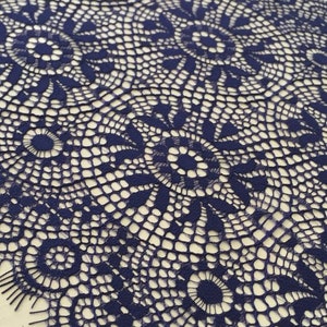 May include: Navy blue lace trim with a delicate floral pattern. The lace has a scalloped edge and is perfect for adding a touch of elegance to any project.