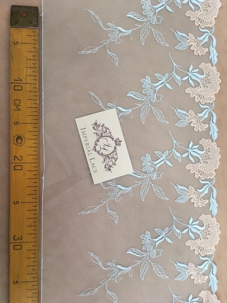 K&ouml;nnte beinhalten: Hellblaue und wei&szlig;e florale Spitzenborte mit einem gewellten Rand. Die Spitze befindet sich auf einem beigefarbenen Hintergrund und ist 20 cm lang. Der Text "Imperial Lace" ist auf einer wei&szlig;en Karte sichtbar.