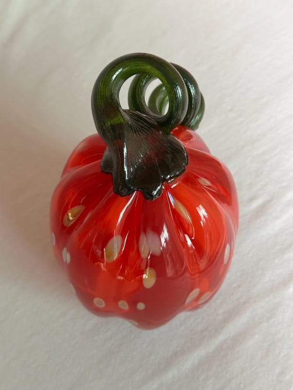 A one-of-a-kind hand-blown glass pumpkin in fiery red and orange — the kind of sculptural fall decor that looks like it belongs in a gallery, not a big-box store.