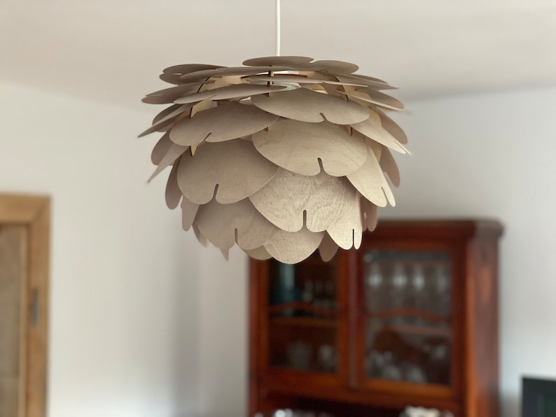 Wood pendant light. Light brown colour. Old wooden cupboard in the background.On the left part of the door to the room is seen