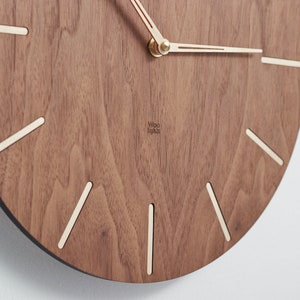 Details of the wooden wall clock. Unique and intriguing arrangement of wood grain gives each clock a distinctive character. The balanced contrast between the clock face and the indexes makes it easier to read the time while ensuring an elegant look.