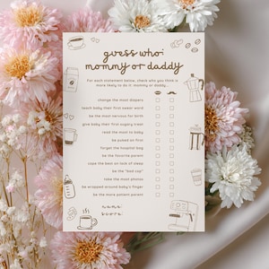 May include: A rectangular game card titled guess who: mommy or daddy with brown text and line art illustrations of coffee items and baby gear. The card features a list of statements with checkboxes for mommy or daddy, plus name and score lines.