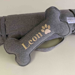 Handmade pewter grey herringbone tweed standard bone toy. personalised name embroidery in gold thread and pawprint icon. matching rolled up picnic pad / travel mat.