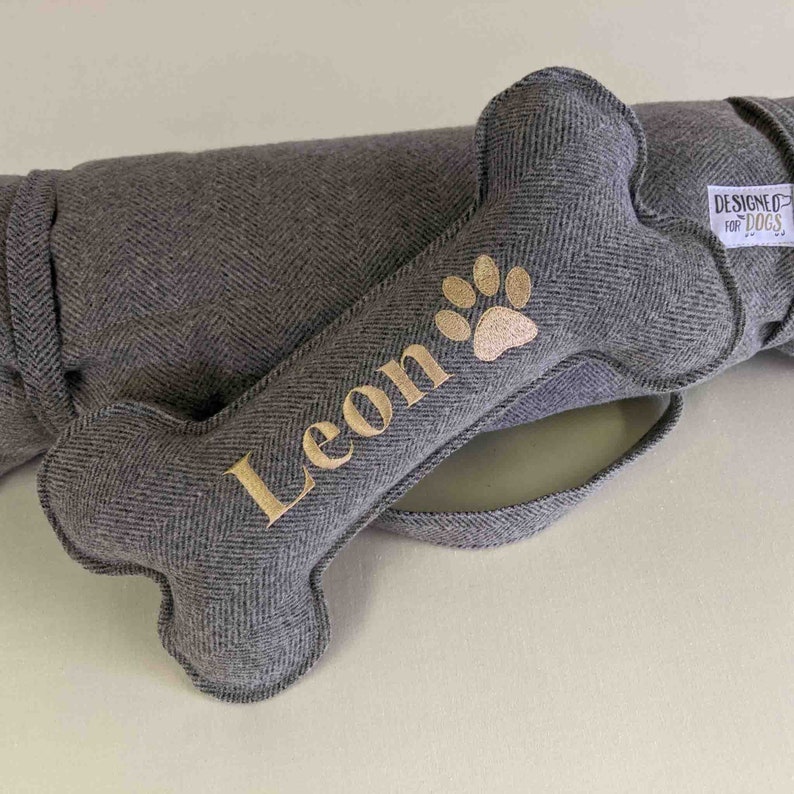 Handmade pewter grey herringbone tweed standard bone toy. personalised name embroidery in gold thread and pawprint icon. matching rolled up picnic pad / travel mat.