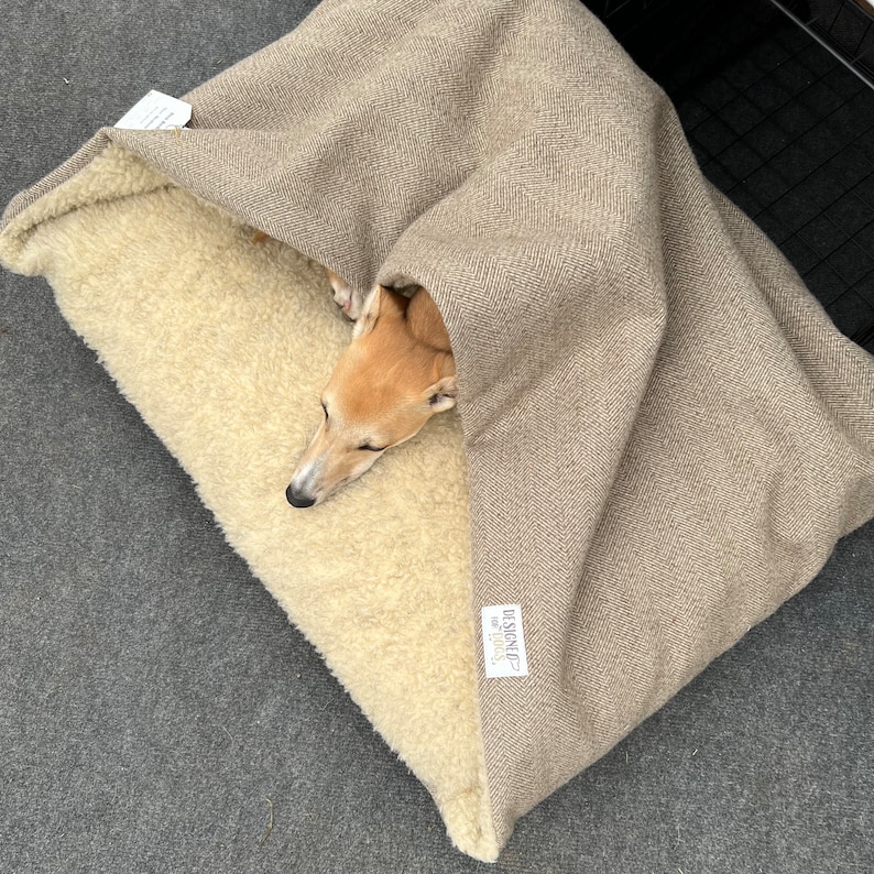 whippet dog sleeping in handmade doggy den / cave bed. envelope opening.  outer fabric stone brown herringbone tweed lined with oatmeal faux sheepskin fleece. machine washable cover. memory foam and orthopaedic foam crumb inner cushion.