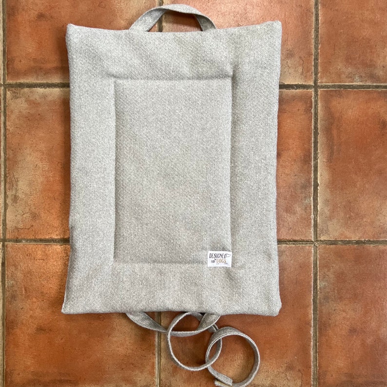 laid out  handmade picnic pad / travel mat in dove (lighter) grey herringbone twee. matching handles and straps waterproof backing and lined with wadding for comfort.