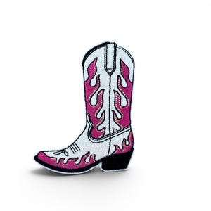 May include: Embroidered patch of a white cowboy boot with a pink flame design. The boot has a black heel and a white upper with pink flames. The patch is designed to be ironed on or sewn onto clothing or accessories.