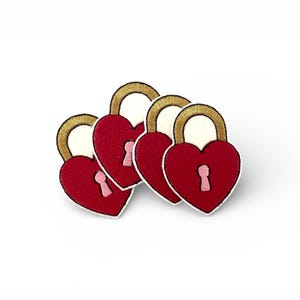 May include: Embroidered heart-shaped lock patches in red with gold and white detailing. Each patch features a keyhole. The patches are arranged in an overlapping pattern against a white background.