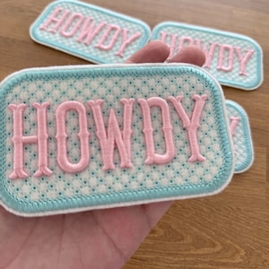 May include: Four light blue and white embroidered patches with the word "HOWDY" in pink lettering.