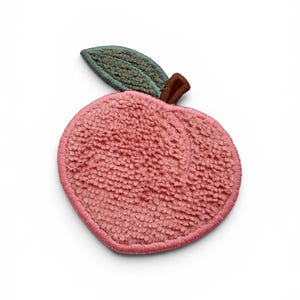 May include: A peach-shaped embroidered patch featuring a textured pink surface with a dark pink stitched border. The design includes a single sage green leaf with a brown stem, all rendered in a plush, looped thread finish on a white background.