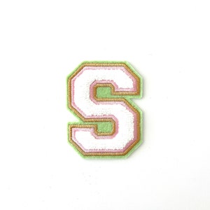 May include: A white felt letter S with a pink and green outline. The letter is in a varsity style font.
