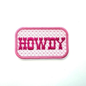 May include: Pink embroidered patch with the word "HOWDY" in a white rectangle with a pink border.