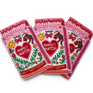 May include: Three embroidered patches in a matchbox design. Each patch features a pink background with the text "YOU ARE MY" and "PERFECT MATCH". The design includes a tiger, sun, flowers, and the words "QUALITY SAFETY MATCHES".