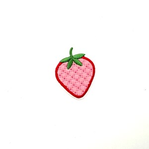 May include: A pink embroidered strawberry patch with green leaves and a red outline.
