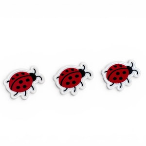 May include: Three ladybird patches with a red body, black spots, and black antennae. Each patch has a white border. These patches are ideal for adding a decorative touch to clothing, bags, or other fabric items.