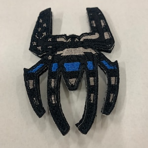 May include: Black and gray embroidered patch with a spider design. The spider's body is an American flag with a blue and white thin blue line across the middle.