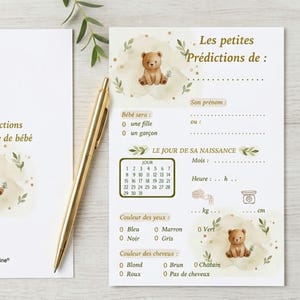Peut inclure: Une carte de prédictions de bébé en papier blanc avec une illustration d'ourson brun, des feuilles vertes et du texte doré. La carte comporte des champs pour le prénom, le sexe, la date, l'heure, le poids, la taille, les yeux et les cheveux, avec un stylo doré.
